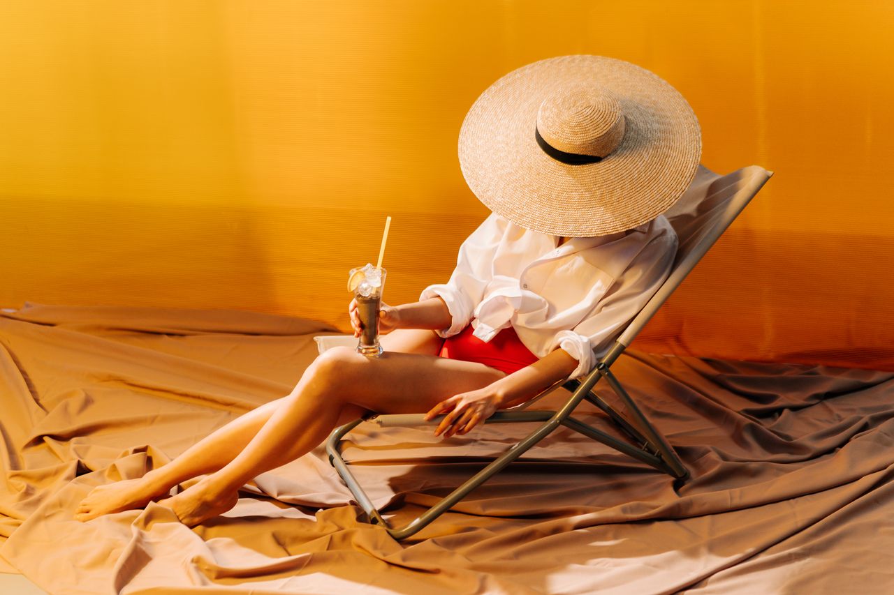 Home Woman in brown hat relaxing indoors with a drink, showcasing summer style and leisure.